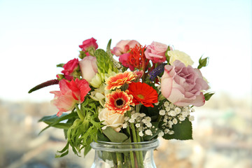 Glass vase with beautiful bouquet of fresh flowers on window background