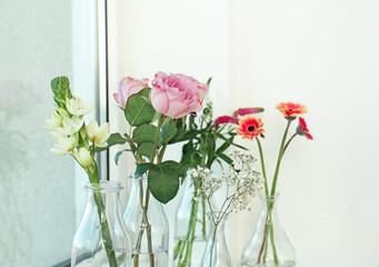 Glass vases with beautiful bouquets of fresh flowers on windowsill