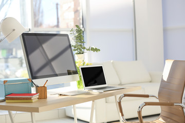Workplace with computer and laptop on table in modern room
