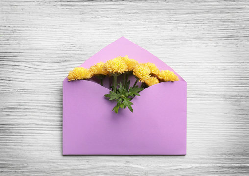 Decorative envelope with chrysanthemum flowers on white wooden background