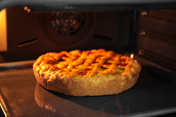 Delicious pie with fruits on baking tray in oven
