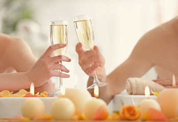 Young couple drinking champagne in spa salon