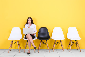 Young woman waiting for job interview on yellow wall background