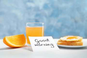 Note with phrase GOOD MORNING and tasty breakfast on table