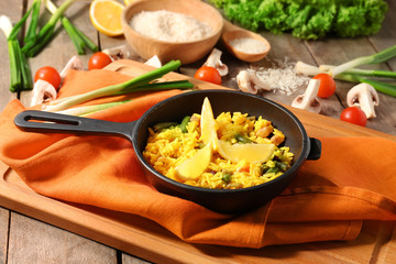Frying pan with traditional vegetable rice on table