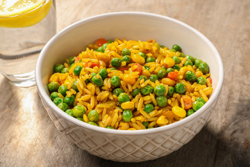 Delicious rice with vegetables in a bowl on table