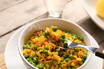 Delicious rice with vegetables in a bowl on table