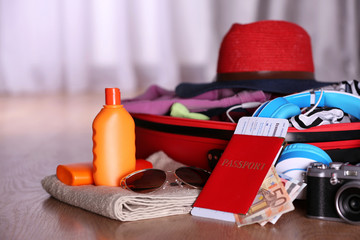 Open suitcase with travel accessories and clothes on blurred background