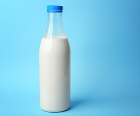Bottle of tasty milk on blue background