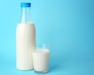 Bottle of tasty milk with glass on blue background