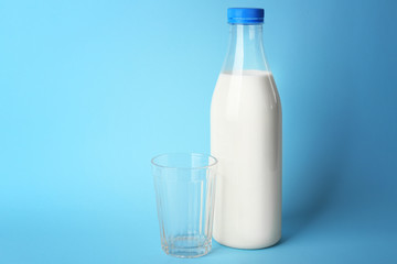 Bottle of tasty milk with glass on blue background
