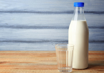 Bottle of tasty milk with glass on wooden table