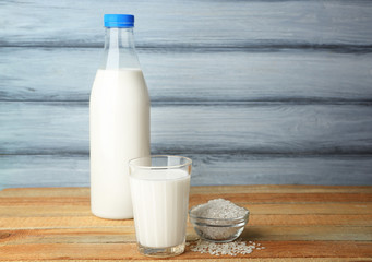 Bottle of tasty rice milk with glass on wooden table