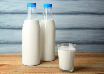Bottles of tasty milk with glass on wooden table