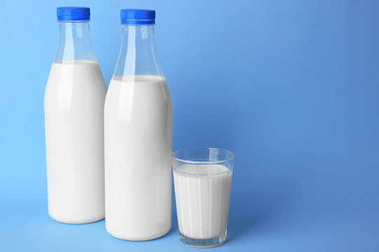 Bottles of tasty milk with glass on blue background
