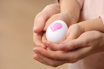 Hands of little child and mother holding Easter egg, closeup