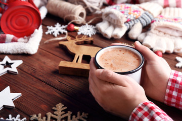Male hands with cup of cocoa and Christmas decorations on wooden background