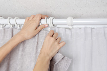 Woman hands installing curtains over window © Africa Studio
