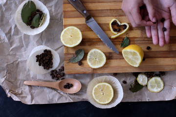 process of cooking in the kitchen, boy holding half a lemon in his hands, on the table next to slices of lemon and coffee beans and spices