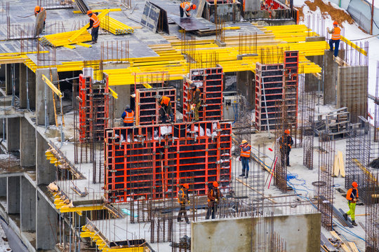 Construction site with a bright yellow formwork and builders in bright multi-colored construction form