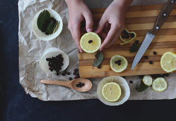 process of cooking in the kitchen, boy holding half a lemon in his hands, on the table next to slices of lemon and coffee beans and spices