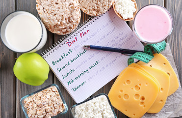 Diary and different dairy products on wooden background