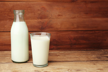 Bottle and glass of milk on wooden background