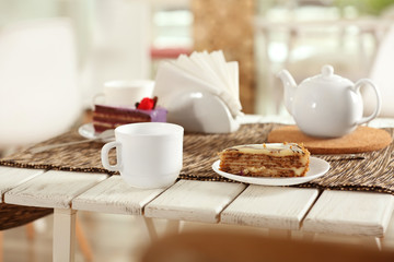 Plate with tasty cake and cup of tea on table in cafe