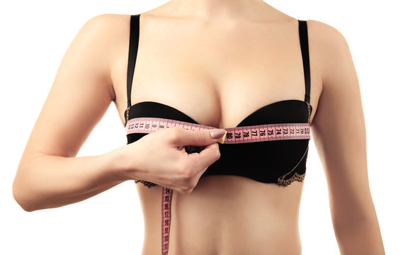 Young woman in black bra with measuring tape on white background, closeup