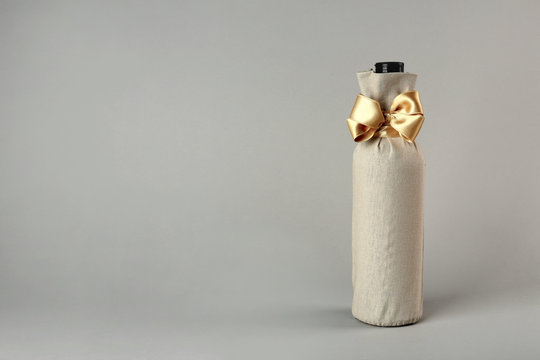 St. Valentine's Day Concept. Wine Bottle In Gift Linen Pouch With Satin Ribbon On Light Background