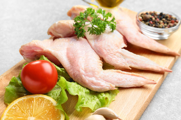 Raw chicken wings with spices on cutting board