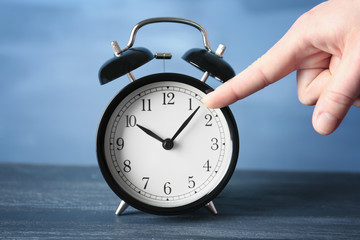 Female hand pointing on alarm clock, closeup
