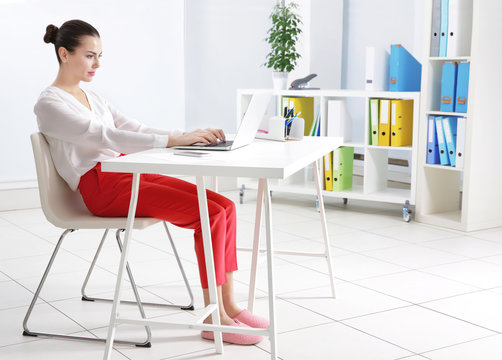 Incorrect posture concept. Young woman sitting at table in modern room