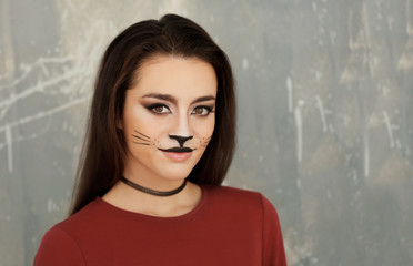 Beautiful young woman with cat makeup on grunge background