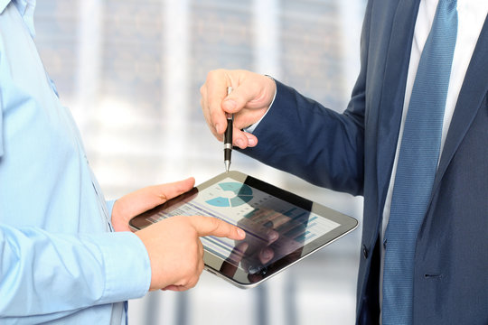 Business colleagues working and analyzing financial figures on a digital tablet