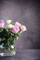 Glass vase with bouquet of beautiful roses on color background