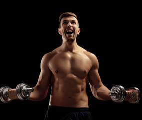 Fototapeta na wymiar Sporty man doing exercises with dumbbells on dark background