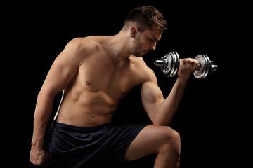 Fototapeta na wymiar Sporty man doing exercises with dumbbell on black background