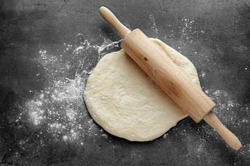 Rolling pin with dough on kitchen table