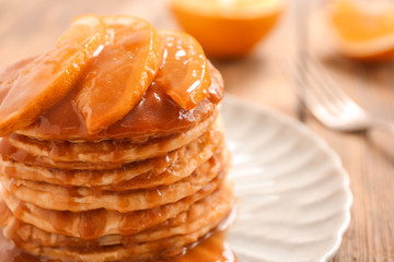 Delicious pancakes with orange slices and syrup, closeup