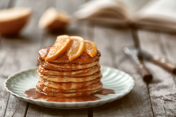 Delicious pancakes with orange slices and syrup on plate