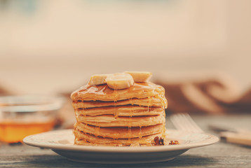 Tasty pancakes with banana, nuts and honey on plate