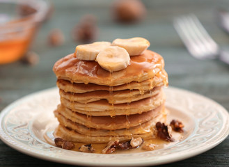 Tasty pancakes with banana, nuts and honey on plate