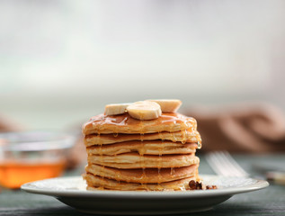 Tasty pancakes with banana, nuts and honey on plate