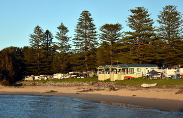 Fototapeta na wymiar Cabins of the Tuross Beach Holiday Park right at the beach in early morning view. Tuross Head is a seaside village on the south coast of New South Wales, Australia.