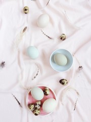 Obraz na płótnie Canvas White and green Easter eggs, quail eggs and feathers on pink textile background. Flat lay, top view. Traditional spring concept. Easter concept.