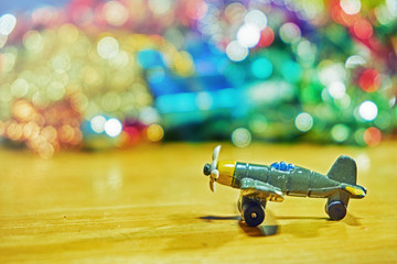 Mini plane on the wooden table in front of glitter background
