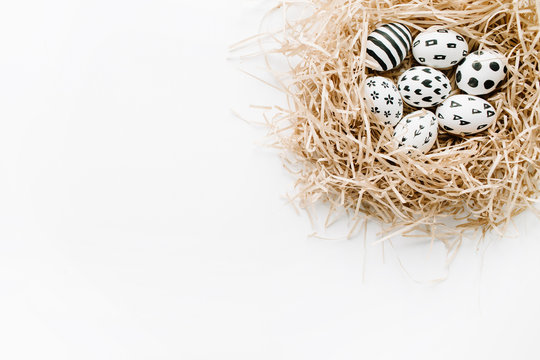 Fancy Easter eggs in nest on white background. Flat lay, top view. Traditional spring concept.