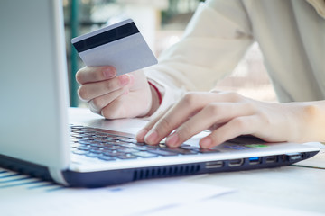 Woman's hands holding a credit card and using smart phone for online shopping.vintage tone