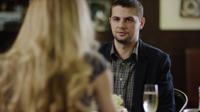 back view of curling blondie telling to partner in restaurant